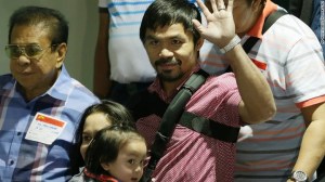 Pacquiao saluda a la multitud al llegar, junto con su esposa Jinkee y su hijo menor Israel (al fondo a la izquierda) el 13 de mayo en el aeropuerto de Filipinas.