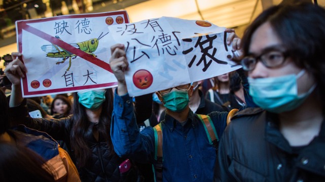 Manifestantes marchan hacia un centro comercial en Shatin, Hong Kong, el 15 de febrero de 2015. Un manifestante sostiene una pancarta con la imagen de una langosta.