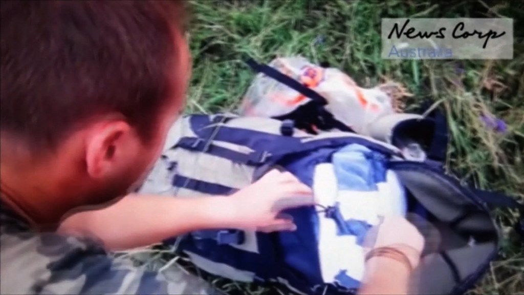 En una de las imágenes del video divulgado por News Corp se ve a un presunto combatiente registrando una mochila en la zona donde cayó el avión. Crédito: News Corp.