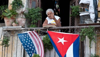 Un cubano saluda desde su balcón decorado con las banderas de Cuba y Estados Unidos en La Habana el 16 de enero de 2015 (Crédito: YAMIL LAGE/AFP/Getty Images)
