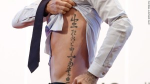 El futbolista británico David Beckham muestra su tatuaje a los aficionados durante su visita a la Universidad de Pekín el 24 de marzo del 2013 en Beijing.