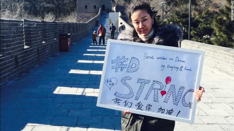 Xu Jin posa con un cartel en apoyo a Dorian en la Gran Muralla China.