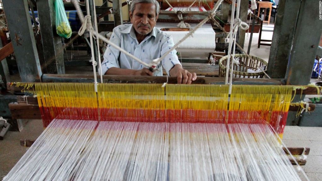 Un hombre indio teje en una fábrica de telares manuales en Ahmadabad, India.