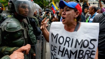 TOPSHOT - A woman with a sign reading "We starve" protests against new emergency powers decreed this week by President Nicolas Maduro in front of a line of riot policemen in Caracas on May 18, 2016. Public outrage was expected to spill onto the streets of Venezuela Wednesday, with planned nationwide protests marking a new low point in Maduro's unpopular rule. / AFP / FEDERICO PARRA (Photo credit should read FEDERICO PARRA/AFP/Getty Images)