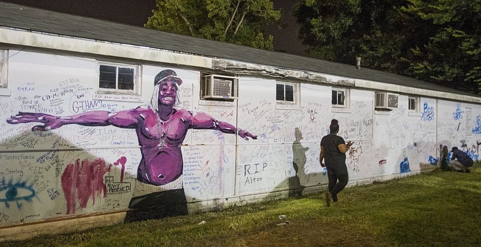 Una persona que lee los mensajes escritos en la pared junto a la tienda donde Alton Sterling murió a tiros el 6 de julio de 2016, en Baton Rouge, Louisiana. Crédito: Mark Wallheiser / Getty Images.