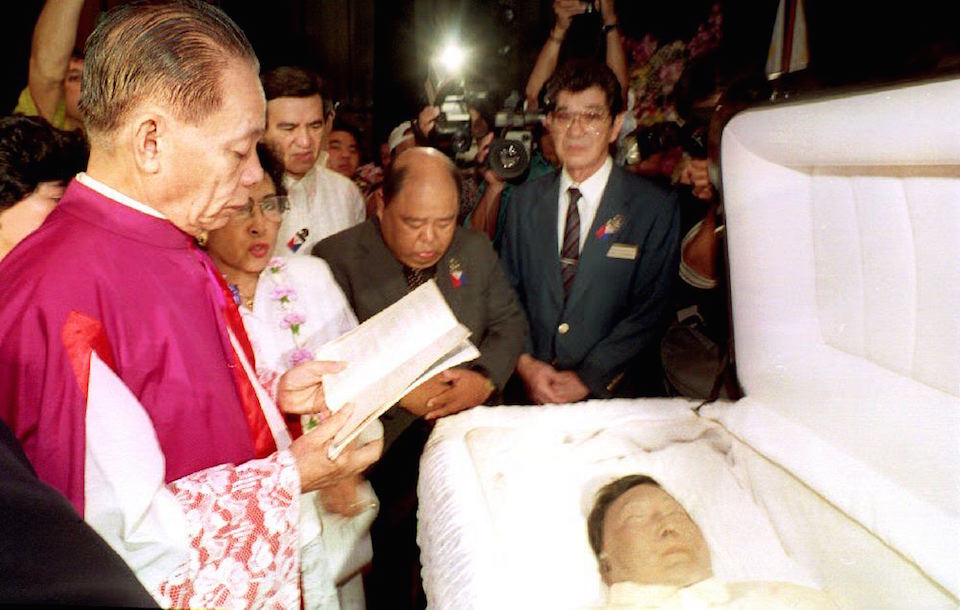 El regreso a Filipinas,. HONOLULU, HI - SEPTEMBER 4: Msgr. Domingo Nebres (L) flanked by the sister of the late Philippine President Ferdinand Marcos, Fortuna Barba, recites prayers over the open casket of Marcos. Services began early 04 September 1993 preparing to take Marcos' body back to be buried in the Philippines. He died in exile in Honolulu in 1989. (Photo credit should read GEORGE F.LEE/AFP/Getty Images)