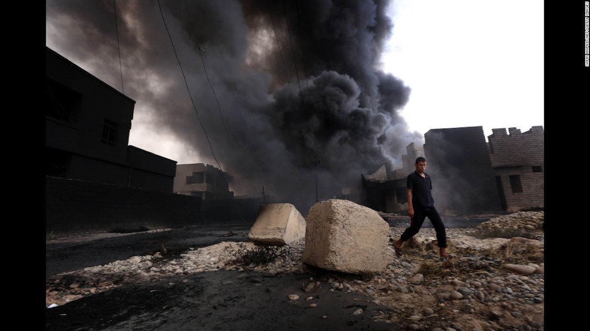 Un hombre Iraquí camina cerca de una columna de humo que sale de los pozos de petróleo incendiados por ISIS antes de huir de la región productora de crudo de Qayyarah en agosto 30 de 2016. 