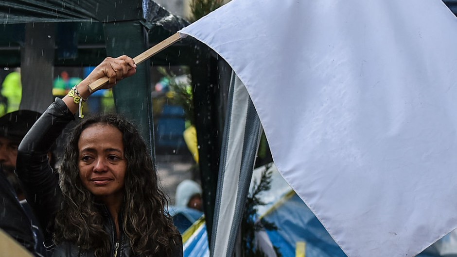 TOPSHOT - A woman cries as she flutters a white flag during a demo for the immediate implementation of the agreement between the Colombian government and the FARC guerrillas at Bolivar Square in Bogota on November 18, 2016. / AFP / Luis Acosta (Photo credit should read LUIS ACOSTA/AFP/Getty Images)