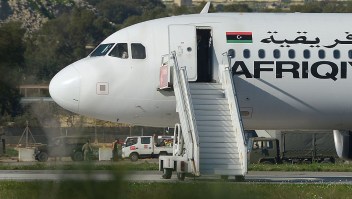 A picture taken on December 23, 2016 shows a group of hostages being released in Valletta, Malta, from the Afriqiyah Airways A320 after it was hijacked from Libya. A man who said he was armed with a grenade hijacked a Libyan plane which landed on Malta Friday with 118 people on board, Malta's prime minister and government sources on the Mediterranean island said. After more than an hour on the tarmac, the plane's door opened and a first group of women and children were seen descending a mobile staircase. "First group of passengers, consisting of women and children, being released now," Prime Minister Joseph Muscat said on Twitter, adding in a later tweet that 50 passengers in all were being let off the plane. / AFP / Matthew Mirabelli / Malta OUT (Photo credit should read MATTHEW MIRABELLI/AFP/Getty Images)