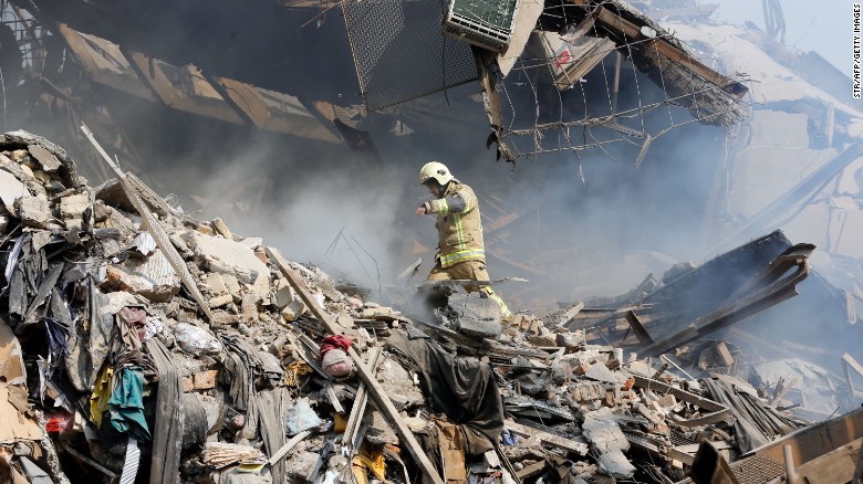 Un bombero iraní camina sobre los escombros que dejó el derrumbe del edificio de Plasco.