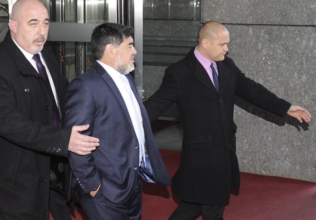 Former Argentiniar football player Diego Armando Maradona (C) leaves the Mirasierra Hotel with a security detail on February 15, 2017 after speaking with Spanish police who were contacted by concerned staff over an argument between Maradona and his girlfriend.   "When the agents and emergency services arrived, those people (Maradona and his girlfriend) showed no sign of injuries and did not press charges, there was just a discussion," police sources told AFP. / AFP / CURTO DE LA TORRE        (Photo credit should read CURTO DE LA TORRE/AFP/Getty Images)