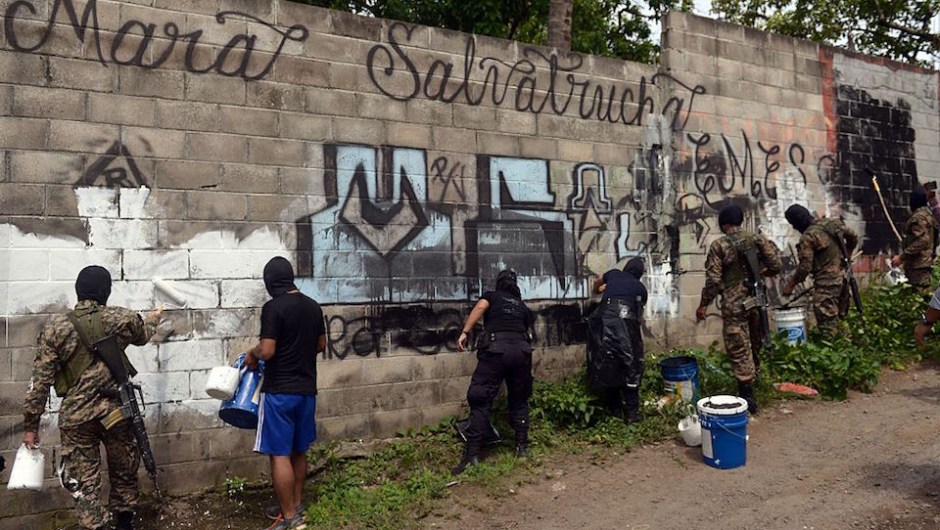 Police officers and soldiers paint over graffiti associated with the Mara Salvatrucha gang in Quezaltepeque, a town 15 km from San Salvador, in an operation to take back gang-controlled neighborhoods, on June 7, 2016. The Salvatrucha (MS-13) and 18th Street gangs are the main cause of the escalation of violence plaguing El Salvador, where an estimated 60,000 people belong to gangs, 15,000 of them in prison. / AFP / Marvin RECINOS (Photo credit should read MARVIN RECINOS/AFP/Getty Images)