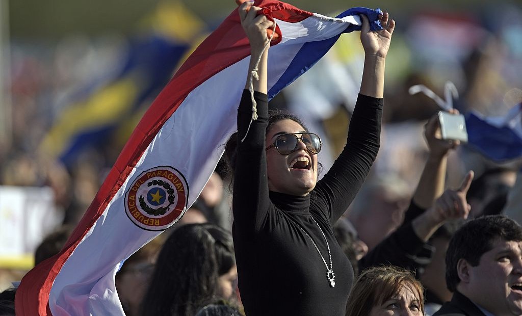 A Catholic faitful holds a Paraguayan national flag as she waits near the altar where Pope Francis will deliver a mass at Nu Guazu field in the outskirts of Asuncion, Paraguay on July 12, 2015. The Pope finishes Sunday his Latin American tour. AFP PHOTO / JUAN MABROMATA (Photo credit should read JUAN MABROMATA/AFP/Getty Images)