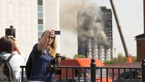 Una mujer toma una 'selfie' con la Torre Grenfell de fondo.