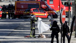 TOPSHOT - EDITORS NOTE: Graphic content / Rescuers cover with a white sheet the body of a man lying in a sealed off area of the Champs-Elysees avenue in Paris, on June 19, 2017 , after a car crashed into a police van before bursting into flames, with the driver being armed, probe sources said. A car burst into flames after it crashed into a police van on the Champs-Elysees avenue in Paris on June 19, police and investigators said, adding that the driver was armed and it appeared to be a "deliberate" act. Authorities said the driver was "most probably dead". / AFP PHOTO / Thomas SAMSON (Photo credit should read THOMAS SAMSON/AFP/Getty Images)