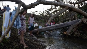 People carry water in bottles retrieved from a canal due to lack of water following passage of Hurricane Maria, in Toa Alta, Puerto Rico, on September 25, 2017. The US island territory, working without electricity, is struggling to dig out and clean up from its disastrous brush with the hurricane, blamed for at least 33 deaths across the Caribbean. / AFP PHOTO / HECTOR RETAMAL (Photo credit should read HECTOR RETAMAL/AFP/Getty Images)