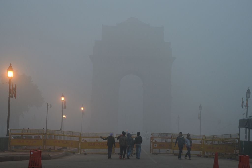 Indian pedestrians walk near the India Gate monument amid heavy smog in New Delhi on November 8, 2017. Delhi shut all primary schools on November 8 as pollution levels hit nearly 30 times the World Health Organization safe level, prompting doctors in the Indian capital to warn of a public health emergency. Dense grey smog shrouded the roads of the world's most polluted capital, where many pedestrians and bikers wore masks or covered their mouths with handkerchiefs and scarves. / AFP PHOTO / SAJJAD HUSSAIN (Photo credit should read SAJJAD HUSSAIN/AFP/Getty Images)