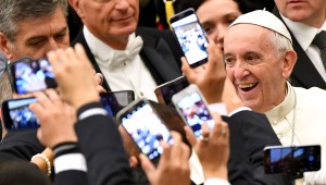TOPSHOT - Pope Francis (R) arrives to lead his weekly general audience at Paul VI hall on December 21, 2016 at the Vatican as people take pictures of him with their cell-phone. / AFP / Alberto PIZZOLI (Photo credit should read ALBERTO PIZZOLI/AFP/Getty Images)