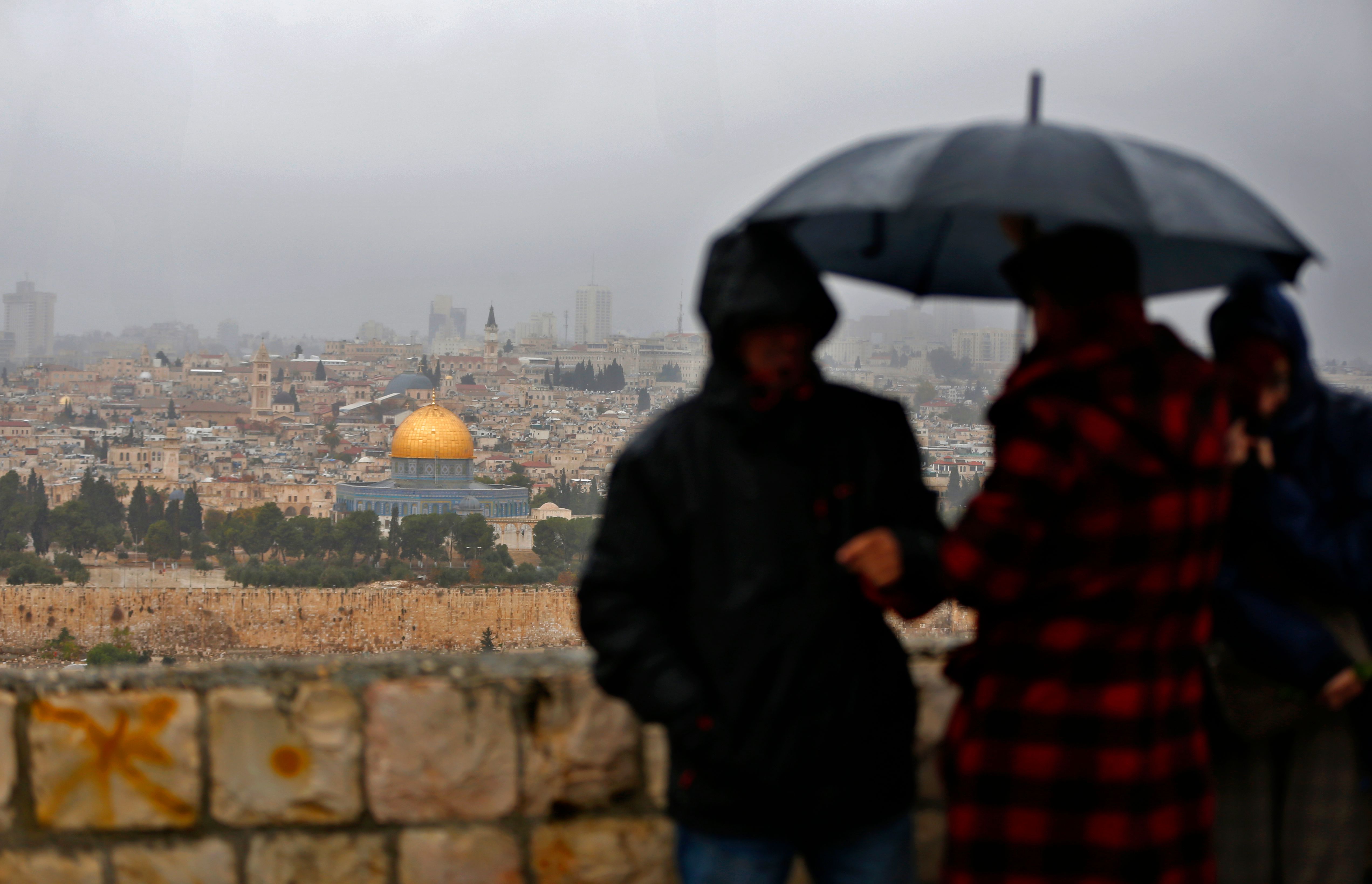People stand at Mount of Olives and look at the Old City of Jerusalem and its Dome of the Rock mosque in the centre, on December 6, 2017. President Donald Trump is set to recognise Jerusalem as Israel's capital, upending decades of careful US policy and ignoring dire warnings from Arab and Western allies alike of a historic misstep that could trigger a surge of violence in the Middle East. / AFP PHOTO / AHMAD GHARABLI (Photo credit should read AHMAD GHARABLI/AFP/Getty Images)