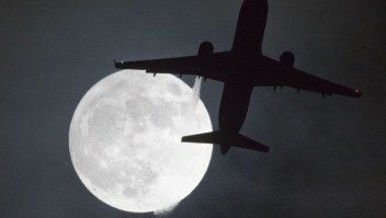 TOPSHOT - A plane flys in front of a "super moon" or "wolf moon" on its approach to London Heathrow Airport on January 1, 2018. / AFP PHOTO / Justin TALLIS (Photo credit should read JUSTIN TALLIS/AFP/Getty Images)
