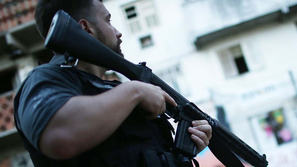 RIO DE JANEIRO, BRAZIL - MAY 26: A civil police officer holds his weapon in the pacified Pavao-Pavaozinho community at the start of an investigation into the death of dancer Douglas Rafael da Silva Pereira on May 26, 2014 in Rio de Janeiro, Brazil. Police re-constructed the death of Pereira this afternoon. Protests and shootings broke out following the discovery of Pereira's body in the 'favela' last month. Ahead of the World Cup, some of Rio's pacified favelas have seen an increase in violence, including a number of shootings in Pavao-Pavaozinho. Around 10,000 people live in the Cantagalo and Pavao-Pavaozinho communities with a total of around 1.6 million Rio residents residing in shantytowns, many of which are controlled by drug traffickers. (Photo by Mario Tama/Getty Images)