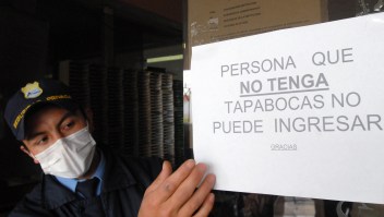 Un miembro de seguridad muestra uno de los carteles que se colgaron en Colombia por la crisis del AH1N1 en 2009. Foto de archivo. (Crédito: LUIS RAMIREZ/AFP/Getty Images)