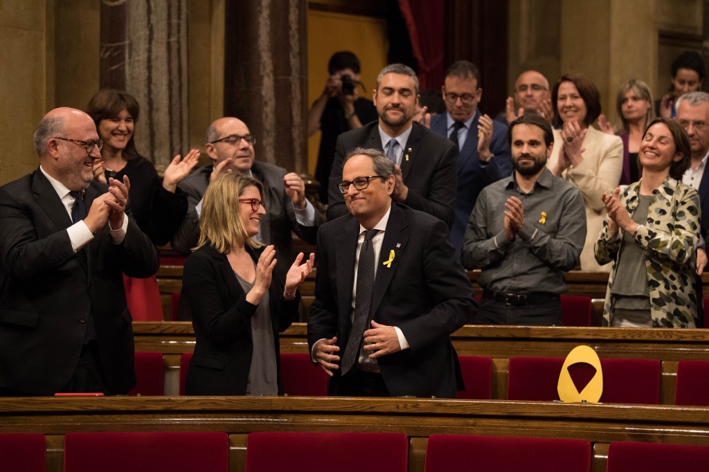 Quim Torra recibe el aplauso de la bancada tras conseguir ser nombrado presidente de la Generalitat de Cataluña. A su lado, uno de los asientos vacíos de los diputados ausentes, señalado con un lazo amarillo como símbolo del independentismo. (Crédito: David Ramos/Getty Images)