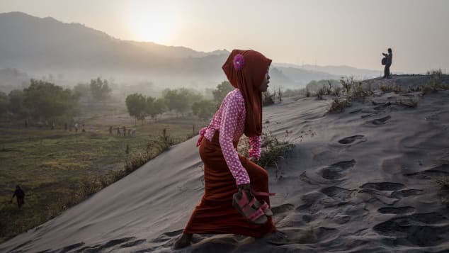 Una mujer musulmana camina sobre el "mar de arenas" mientras se prepara para la oración en la playa Parangkusumo en Yogyakarta, Indonesia.