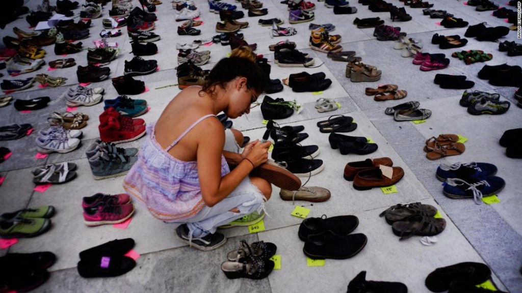 Una mujer coloca uno de los cientos de zapatos en memoria de los fallecidos por el huracán María frente al Capitolio de Puerto Rico, en San Juan, el viernes 1 de junio de 2018. (Crédito: AP Photo/Ramon Espinosa)
