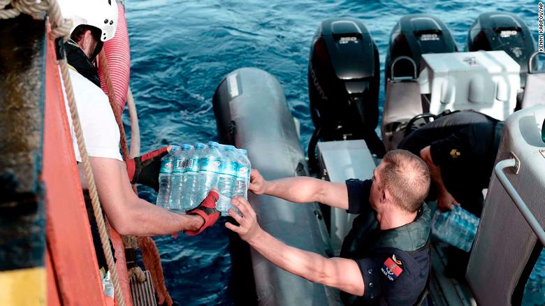 Un funcionario de la marina de Malta reparte agua al barco de rescate. (Crédito: Kenny Karpov/SOS Mediterranee via AP)