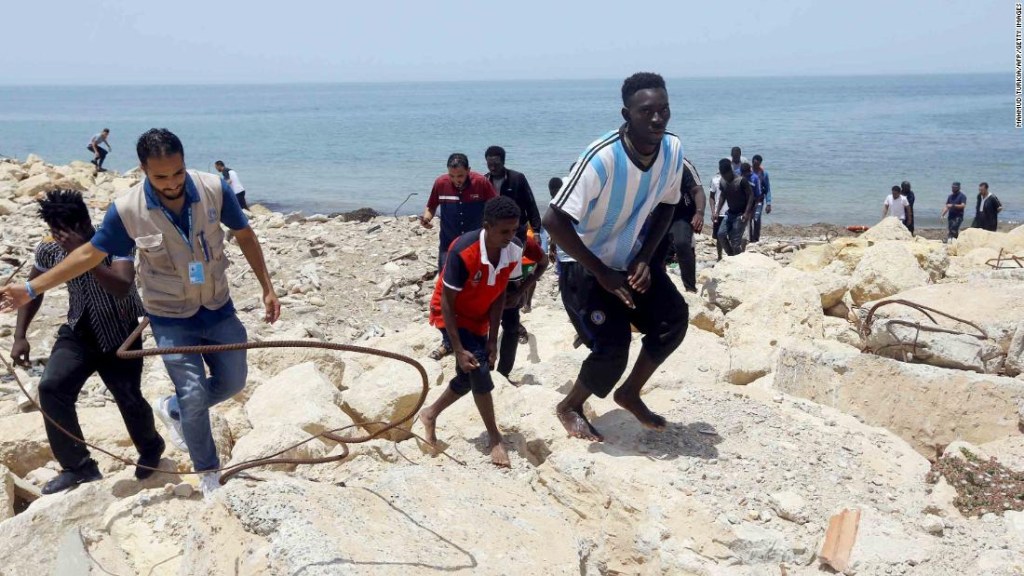 Los migrantes que sobrevivieron al hundimiento escalan la costa rocosa de al-Hmidiya, al este de la capital, Trípoli. (Crédito: MAHMUD TURKIA/AFP/Getty Images)