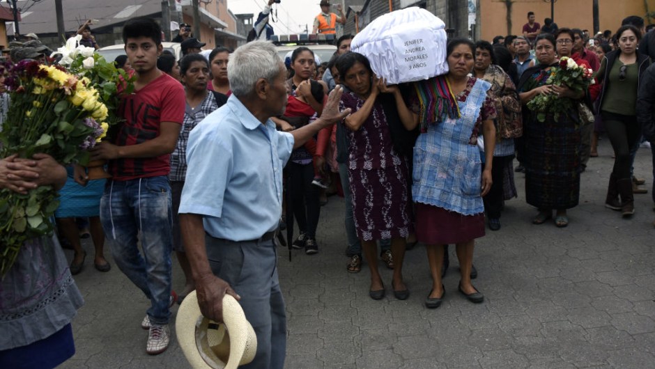 TOPSHOT - Two women carry the coffin of a little girl who died, following the eruption of the Fuego volcano, along the streets of Alotenango municipality, Sacatepequez, about 65 km southwest of Guatemala City, on June 4, 2018. - Rescue workers Monday pulled more bodies from under the dust and rubble left by an explosive eruption of Guatemala's Fuego volcano, bringing the death toll to at least 62. (Photo by JOHAN ORDONEZ / AFP) (Photo credit should read JOHAN ORDONEZ/AFP/Getty Images)