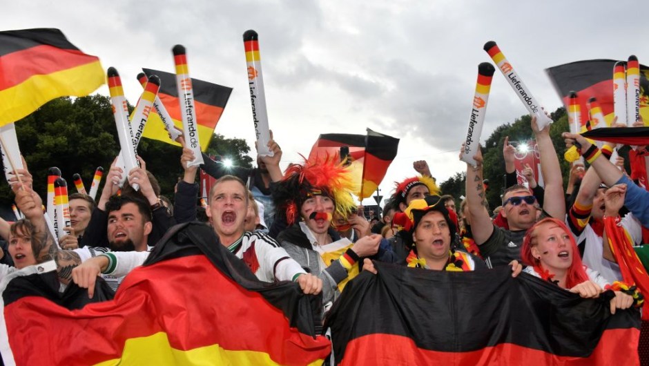 Supporters of the German national football team wave national flags as they watch on a giant screen the Russia 2018 World Cup Group F football match between Germany and Sweden on June 23, 2018 in Berlin. (Photo by John MACDOUGALL / AFP) (Photo credit should read JOHN MACDOUGALL/AFP/Getty Images)