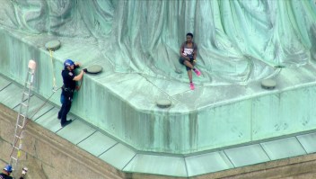 Una mujer trepa la Estatua de la Libertad