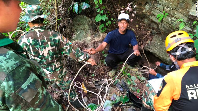 Expertos voluntarios de montañismo se preparan para descender a una abertura en la roca para investigar si hay una ruta hacia la cueva donde están los niños. Están acompañados por trabajadores de la autoridad del Parque Nacional y soldados tailandeses.