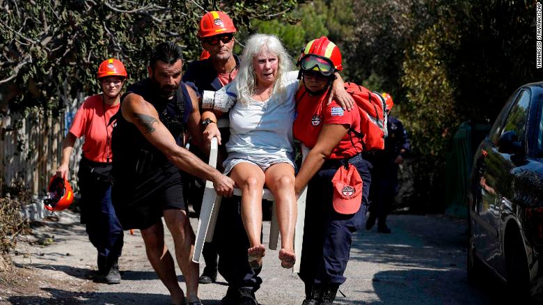 Miembros de los equipos de rescate llevan a una mujer herida en los incendios de Mati, en Grecia. (Crédito: AP Photo/Thanassis Stavrakis)