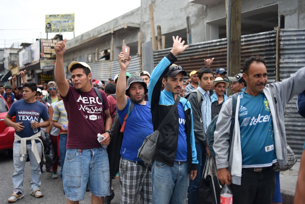 Honduran migrants heading to the United States hold up their hands as they arrive at the Casa del Migrante (Migrant's House) in Guatemala City on October 17, 2018. - A migrant caravan set out on October 13 from the impoverished, violence-plagued country and was headed north on the long journey through Guatemala and Mexico to the US border. President Donald Trump warned Honduras he will cut millions of dollars in aid if the group of about 2,000 migrants is allowed to reach the United States. (Photo by JOHAN ORDONEZ / AFP) (Photo credit should read JOHAN ORDONEZ/AFP/Getty Images)