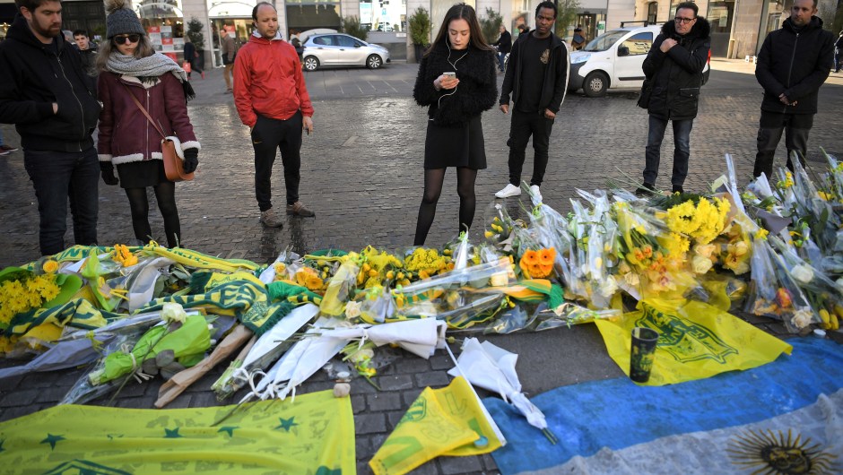 FC Nantes football club supporters looks at flowers and candles placed in the main square of the city of Nantes, western France, two days after it was announced that the plane carrying Argentinian forward Emiliano Sala vanished during a flight from Nantes to Cardiff in Wales, on January 23, 2019. - The 28-year-old Argentine striker is one of two people still missing after contact was lost with the light aircraft he was travelling on, on January 21, 2019 night. Sala was on his way to the Welsh capital to train with his new teammates for the first time after completing a £15 million pounds sterling ($19 million US dollars) move to Cardiff City from French side Nantes on January 19. (Photo by LOIC VENANCE / AFP) (Photo credit should read LOIC VENANCE/AFP/Getty Images)
