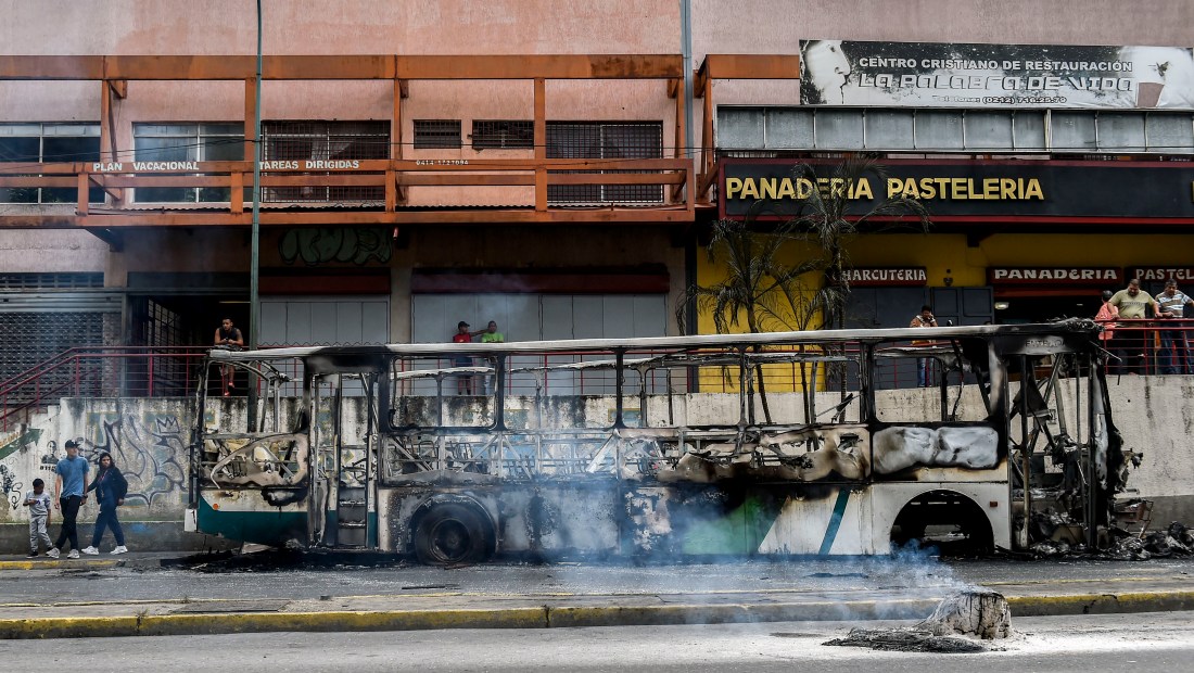 View of a burned bus, that was set up on fire in Caracas on the eve of a march called by Venezuelan opposition on the anniversary of 1958 uprising that overthrew military dictatorship, on January 23, 2019. - At least four people have died following overnight clashes ahead of Wednesday's rival protests in Venezuela by supporters and opponents of President Nicolas Maduro, two days after a failed mutiny by soldiers hoping to spark a movement that would overthrow Maduro, police and non-governmental organizations said. (Photo by Luis ROBAYO / AFP) / The erroneous mention[s] appearing in the metadata of this photo by Luis ROBAYO has been modified in AFP systems in the following manner: [2019] instead of [2018. Please immediately remove the erroneous mention[s] from all your online services and delete it (them) from your servers. If you have been authorized by AFP to distribute it (them) to third parties, please ensure that the same actions are carried out by them. Failure to promptly comply with these instructions will entail liability on your part for any continued or post notification usage. Therefore we thank you very much for all your attention and prompt action. We are sorry for the inconvenience this notification may cause and remain at your disposal for any further information you may require. (Photo credit should read LUIS ROBAYO/AFP/Getty Images)
