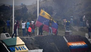 Demonstrators opposed to the government of Nicolas Maduro take down a Venezuelan flag on the border between Venezuela and Pacaraima, Roraima state, Brazil, where clashes erupted amid efforts to take aid into the crisis-hit country, on February 23, 2019. - A high-risk opposition campaign to deliver humanitarian aid into Venezuela descended into chaos Saturday after President Nicolas Maduro's security forces fired on demonstrators and aid trucks were set ablaze as his blockade held firm. Two people, including a 14-year-old boy, were killed in clashes with security forces on the Brazil-Venezuela border amid efforts to bring in aid there, a human rights group said. (Photo by Nelson Almeida / AFP) (Photo credit should read NELSON ALMEIDA/AFP/Getty Images)