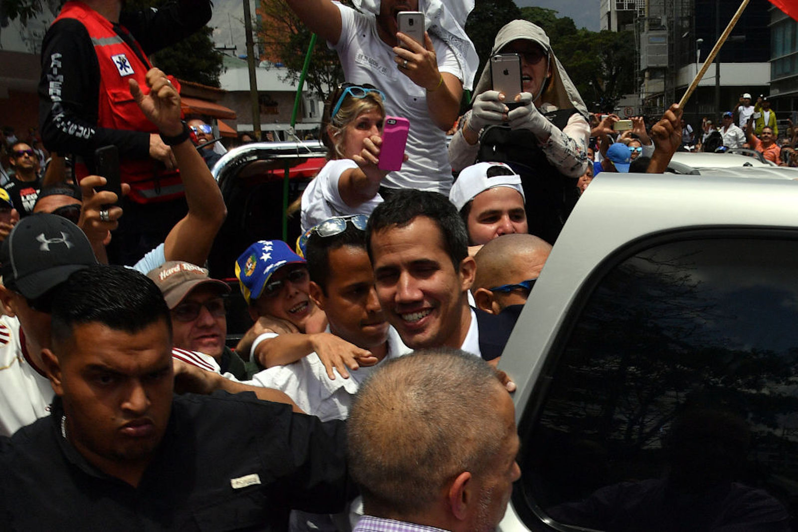 Venezuelan opposition leader and self-proclaimed acting president Juan Guaido (C) is surrounded by supporters upon his arrival in Caracas on March 4, 2019. - Venezuela's opposition leader Juan Guaido was mobbed by supporters, media and the ambassadors of allied countries as he returned to Caracas on Monday, defying the threat of arrest from embattled President Nicolas Maduro's regime. Just before his arrival, US Vice President Mike Pence sent a warning to Maduro to ensure Guaido's safety. (Photo by Yuri CORTEZ / AFP) (Photo credit should read YURI CORTEZ/AFP/Getty Images)