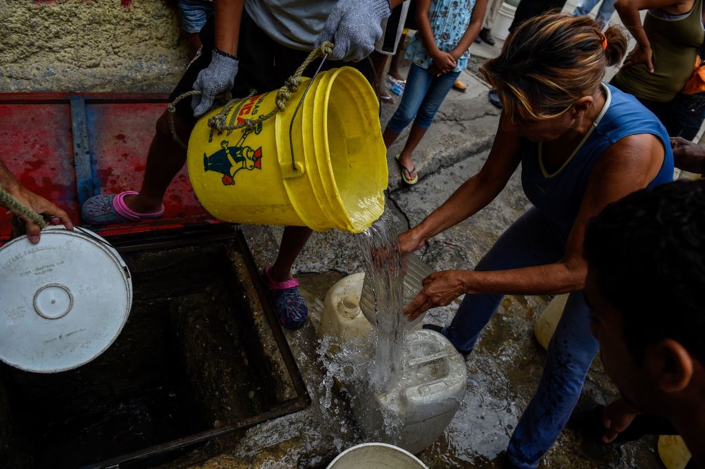 People draw water from a spring water tank to be used in their toilets, at Petare neighborhood in Caracas on April 1, 2019. - Venezuela's President Nicolas Maduro announced 30 days of electricity rationing Sunday, after his government said it was shortening the working day and keeping schools closed due to blackouts. (Photo by Federico Parra / AFP) (Photo credit should read FEDERICO PARRA/AFP/Getty Images)