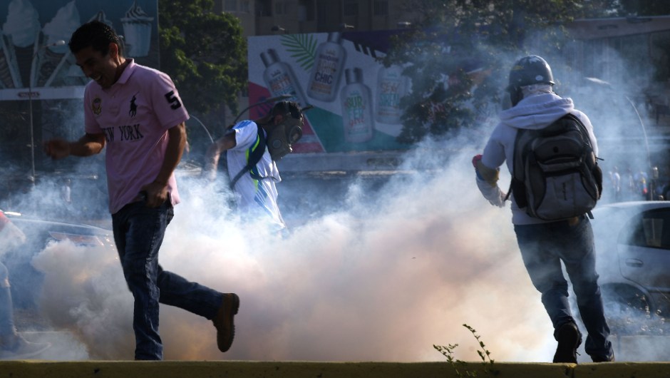 Un grupo de personas huye de los gases lacrimógenos durante los enfrentamientos con las fuerzas de seguridad en Caracas el 30 de abril de 2019. Crédito: YURI CORTEZ / AFP / Getty Images