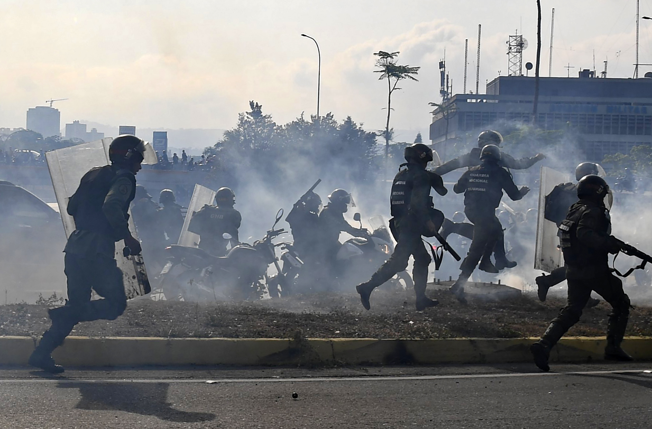 Members of the Bolivarian National Guard loyal to Venezuelan President Nicolas Maduro run under a cloud of tear gas after being repelled with rifle fire by guards supporting Venezuelan opposition leader and self-proclaimed acting president Juan Guaido in front of La Carlota military base in Caracas on April 30, 2019. - Guaido said on Tuesday that troops had joined his campaign to oust President Nicolas Maduro as the government vowed to put down what it called an attempted coup. (Photo by Yuri CORTEZ / AFP) (Photo credit should read YURI CORTEZ/AFP/Getty Images)
