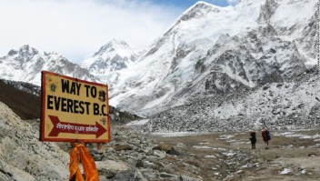 In this photograph taken on April 26, 2018, a sign points towards the Everest base camp while two trekkers walk in the Everest region in Solukhumbu district some 140km northeast of Nepal's capital Kathmandu. - The route is a busy gateway for tourists, climbers and porters heading to the Mount Everest region in Nepal. (Photo by PRAKASH MATHEMA / AFP) (Photo credit should read PRAKASH MATHEMA/AFP/Getty Images)
