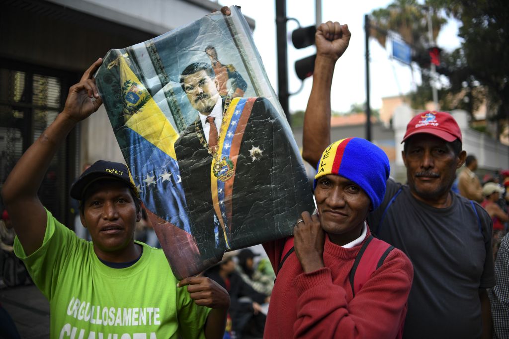 Supporters of the Venezuela's President Nicolas Maduro who stay on vigil in front of the Presidential Palace of Miraflores pose with a poster in Caracas, Venezuela on May 1, 2019. - Demonstrators clashed with police on the streets of the Venezuelan capital Tuesday, spurred by opposition leader Juan Guaido's call on the military to rise up against President Nicolas Maduro -- who said he had defeated an attempted coup. (Photo by YURI CORTEZ / AFP) (Photo credit should read YURI CORTEZ/AFP/Getty Images)
