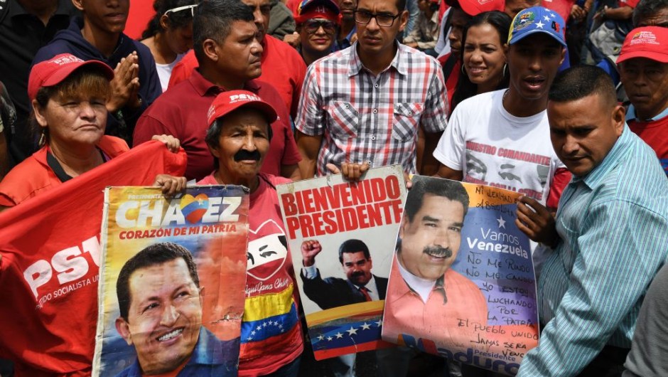 Supporters of Venezuelan President Nicolas Maduro display placard with pictures of Maduro and late leader Hugo Chavez during a rally on May Day in Caracas on May 1, 2019. - Pro- and anti-government rallies were due to take place in Venezuela, a day after violent clashes erupted in the capital following opposition leader Juan Guido's call on the military to rise up against Maduro, who claimed the insurrection had failed. (Photo by Yuri CORTEZ / AFP) (Photo credit should read YURI CORTEZ/AFP/Getty Images)
