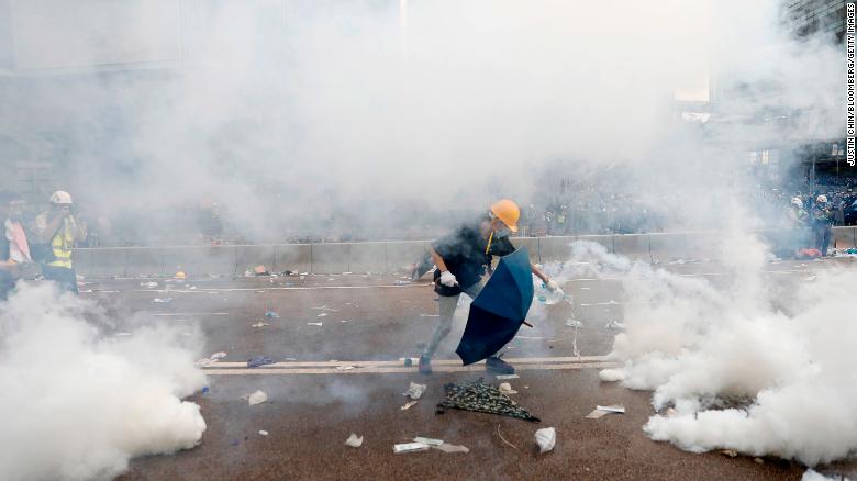 A protester douses a tear gas canisters with water outside the Legislative Council during a protest against a proposed extradition law in Hong Kong, China, on Wednesday, June 12, 2019. Protesters blocking major roads in downtown Hong Kong vowed to stay until the government withdraws controversial legislation that would for the first time allow extraditions to China. Photographer: Justin Chin/Bloomberg via Getty Images