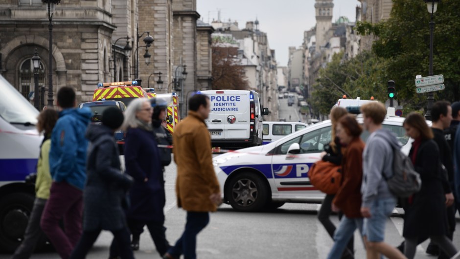 Passerby walk as police vehicle drive toward Paris prefecture de police (police headquarters) after three persons have been hurt in a knife attack on October 3, 2019. - A knife attacker was shot and injured after hurting two people at police headquarters in the historical centre of Paris on October 3, sources told AFP. (Photo by Martin BUREAU / AFP) (Photo by MARTIN BUREAU/AFP via Getty Images)