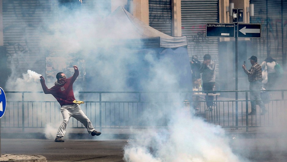 TOPSHOT - A demonstrators throws a tear gas can during clashes between protesters and the police at Plaza de Maipu in Santiago, on October 19, 2019. - Chile's president declared a state of emergency in Santiago Friday night and gave the military responsibility for security after a day of violent protests over an increase in the price of metro tickets. (Photo by Pablo VERA / AFP) (Photo by PABLO VERA/AFP via Getty Images)